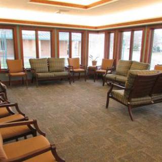 A spacious waiting room featuring multiple chairs and large windows.