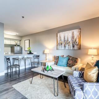 A modern living room with stylish decor, featuring a cozy sofa, elegant coffee table, and a connected kitchen area.