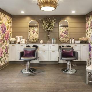 A luxurious hair salon interior with floral wallpaper, elegant chairs, and stylish mirrors.