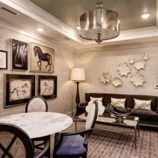 A stylishly decorated living room featuring elegant furniture, modern artwork, and a centerpiece chandelier.