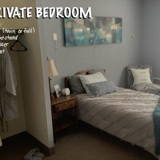 A cozy private bedroom with a neatly made bed, bedside table, and soft lighting.