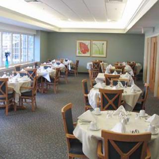 An elegantly set dining room with multiple tables and chairs, ready for guests.