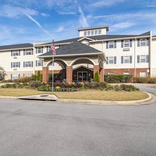A modern residential building with an entrance featuring decorative landscaping and flags.