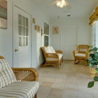 A cozy sunroom with wicker chairs, tiled flooring, and large windows.