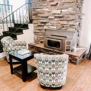 A cozy living room with a stone fireplace, patterned armchairs, and wood flooring.