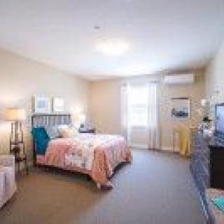 A cozy bedroom with a bed, bedside lamps, and a window providing natural light.