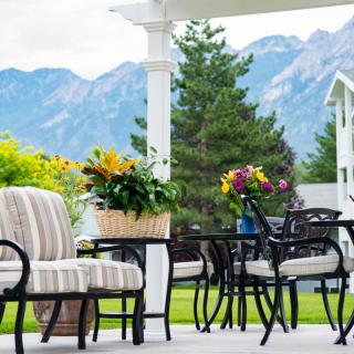 A cozy patio setup with comfortable seating, surrounded by lush greenery and a picturesque mountain backdrop.