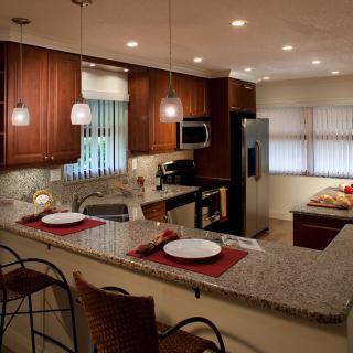 A modern kitchen with a granite countertop, wood cabinets, and stainless steel appliances.