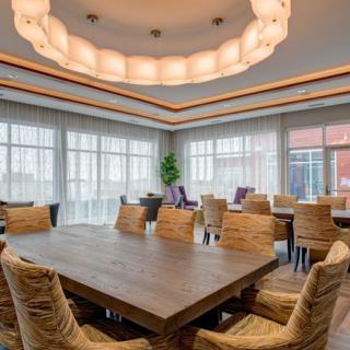 A modern conference room with a large wooden table, comfortable chairs, and ambient lighting.