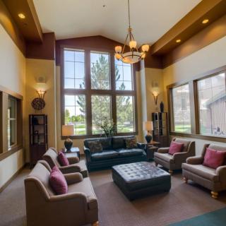A spacious living room with high ceilings, large windows, and comfortable seating.