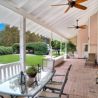 A spacious porch with comfortable seating, ceiling fans, and a view of the landscaped garden.