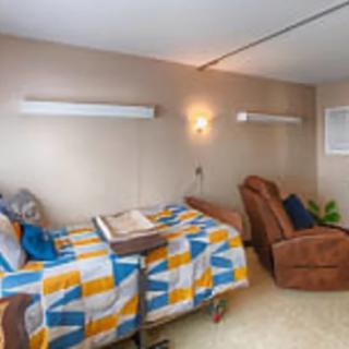 A comfortable and well-furnished hospital room with a colorful quilt on the bed and a recliner chair beside it.
