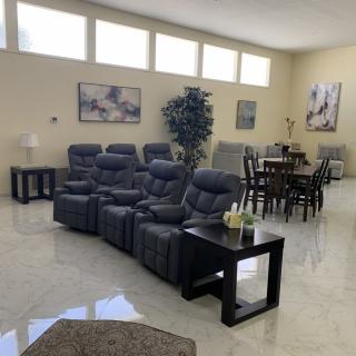 A spacious living room with recliner seating and a dining area, featuring modern decor and ample natural light.