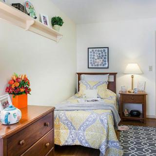 A cozy bedroom with a single bed, decorated with colorful flowers and warm lighting.