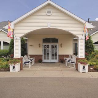 Front entrance of a building with flags and seating area.