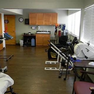 A physical therapy clinic with various exercise equipment and rehabilitation tools.