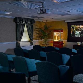A cozy home theater room with seating, a projector screen, and a popcorn machine.