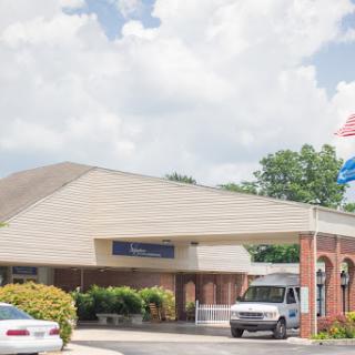 A healthcare facility with flags flying at the entrance on a cloudy day.