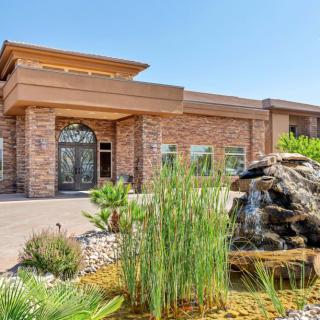 A modern brick building featuring a landscaped entrance with a fountain and greenery.