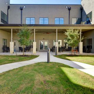 A modern building with a courtyard featuring greenery and outdoor seating.