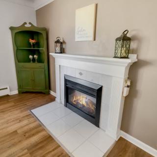A cozy living room featuring a white fireplace with decorative lanterns and a unique green cabinet in the corner.