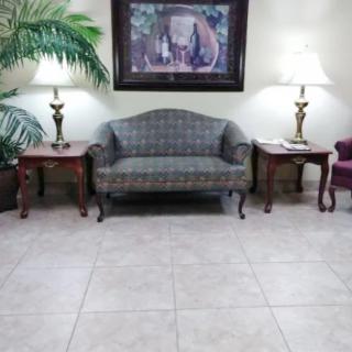 A cozy lobby area with a sofa, side tables, lamps, and a wall painting.