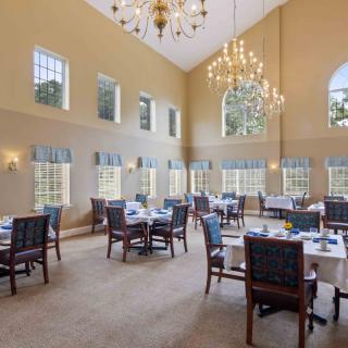 An elegant dining room with large windows, high ceilings, and chandeliers.