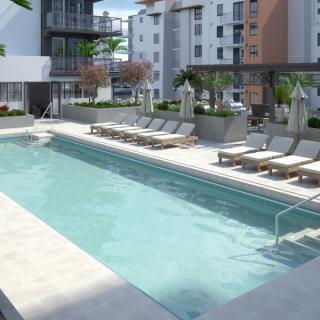 A modern apartment complex featuring an outdoor swimming pool with lounge chairs in an urban setting.