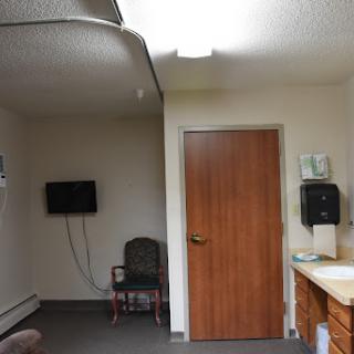 A simple waiting area in an indoor space featuring a television, a door, and basic furniture.