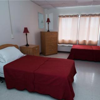 A simple bedroom with two beds and matching red bedspreads.