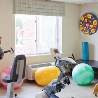 A small exercise room equipped with a stationary bike, colorful exercise balls, and a window providing natural light.
