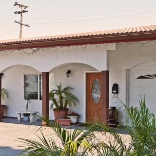 A single-story house with arched windows and doors, featuring potted plants in front.