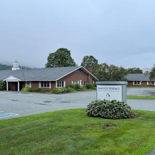 A view of a welcoming building surrounded by well-maintained grass and landscaping under a cloudy sky.