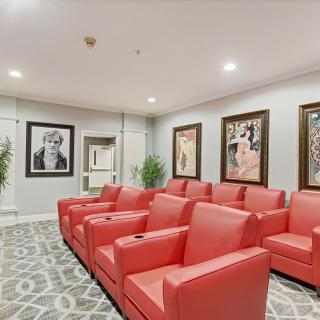 A stylish home theater with red seating and wall art.