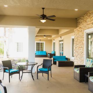 A cozy outdoor patio with modern seating and a ceiling fan.