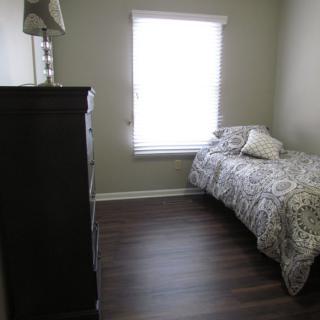 A small bedroom with a single bed, dresser, and a window with blinds.