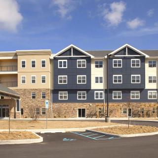 A modern residential apartment building with a mix of blue and beige siding.