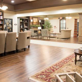 A spacious and elegantly decorated living room with wooden flooring, featuring comfortable seating and a stylish bookshelf.