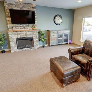 A modern living room with a stone fireplace, mounted TV, and leather seating.