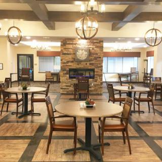 A cozy dining area featuring wooden tables and chairs, warm lighting, and a stone fireplace.