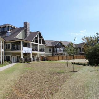 A large residential building with a spacious lawn under a clear blue sky.
