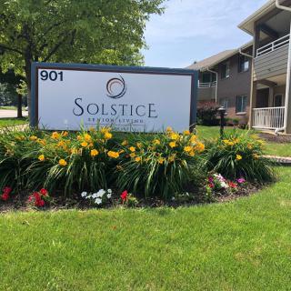 An apartment complex sign surrounded by well-maintained landscaping and flowers.