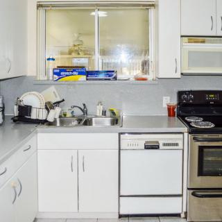 A modern kitchen featuring a stove, dishwasher, and sink with clean dishes on the countertop.