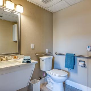 A clean and modern bathroom with a toilet, sink, mirror, and a blue towel hanging on the rack.