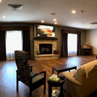 A cozy living room with a fireplace and television, featuring comfortable seating and wooden flooring.