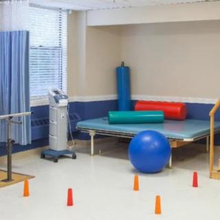 A physical therapy room equipped with exercise equipment including a balance ball, mats, and cones.