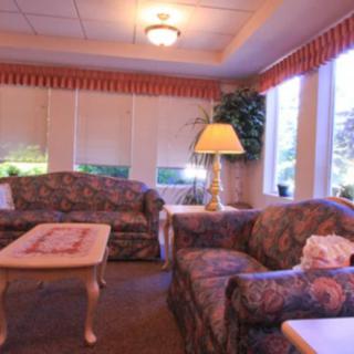 A cozy living room with patterned sofas, a coffee table, and a lamp by the window.