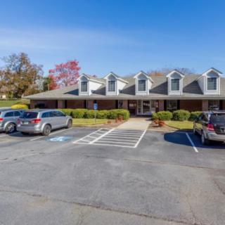 A parking lot in front of a single-story building with multiple cars parked under a clear blue sky.