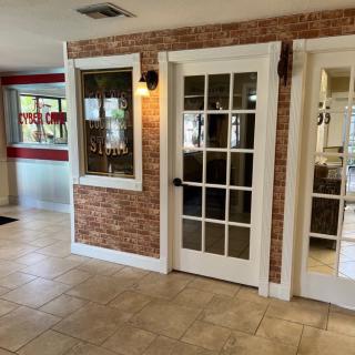 A well-lit lobby area featuring a brick accent wall and glass doors with indoor lighting.