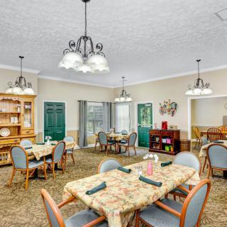 A well-decorated dining room with multiple tables and chairs, illuminated by elegant chandeliers.